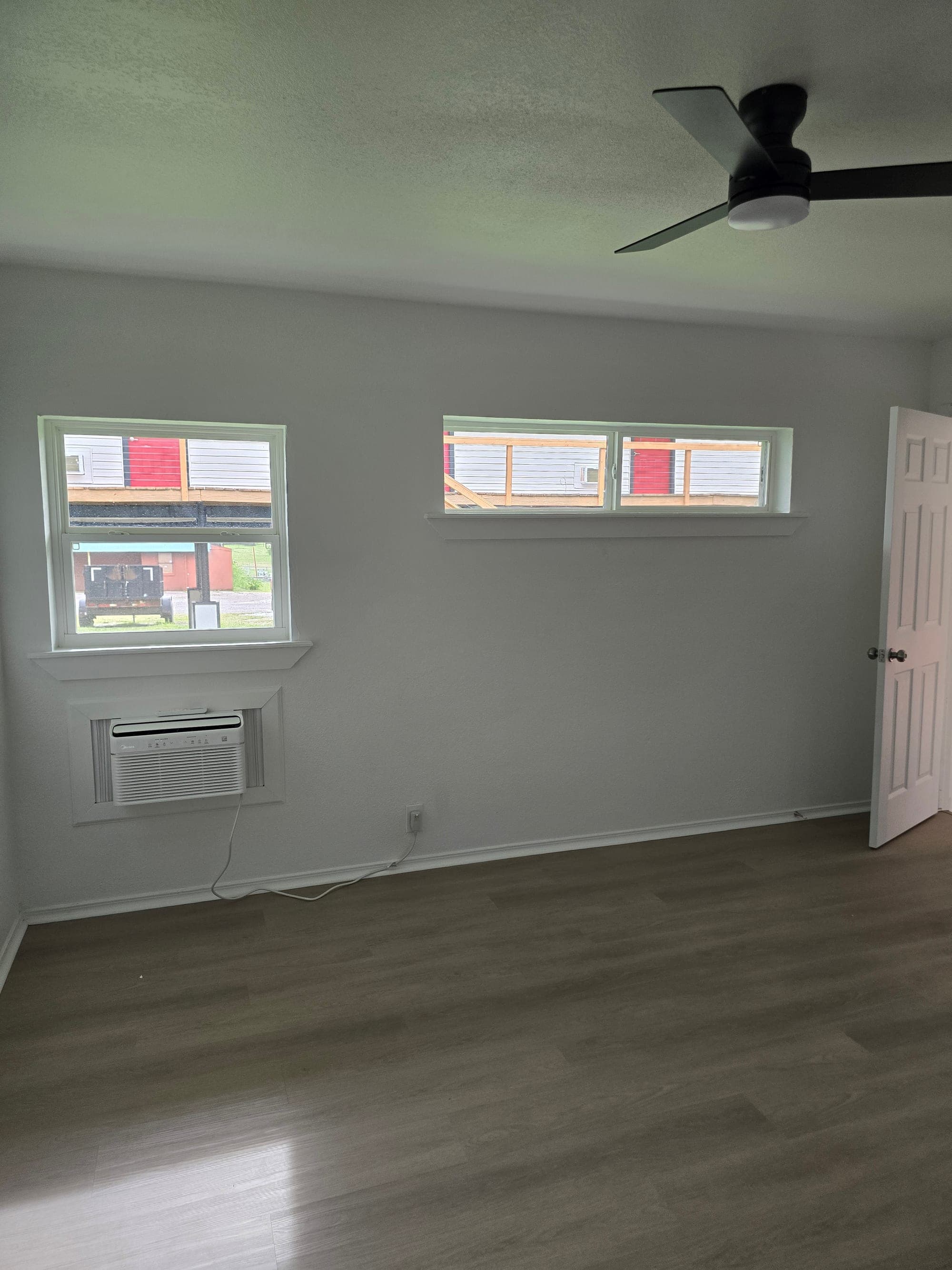 Private bedroom with windows, ceiling fan, and wall air conditioning