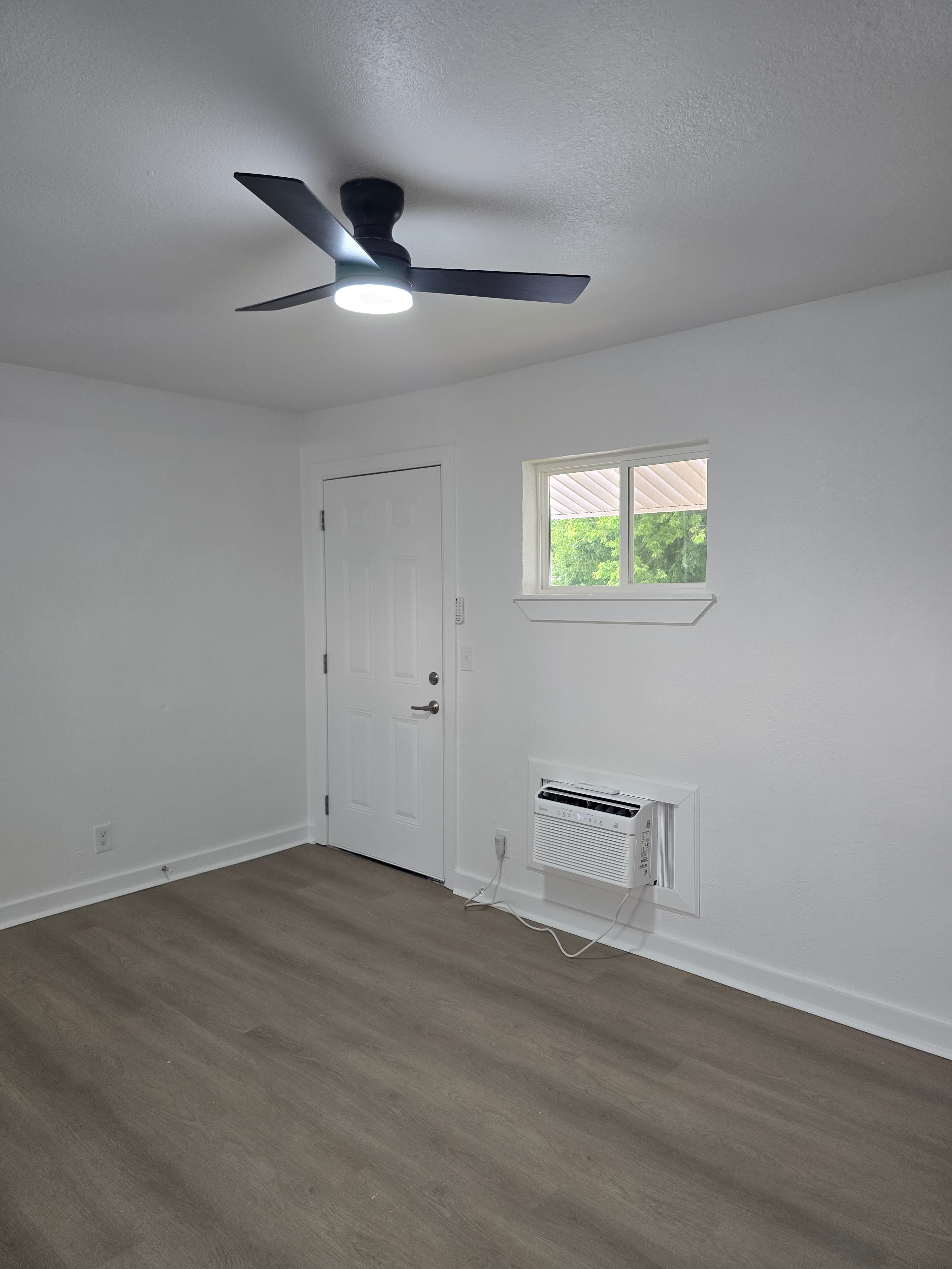 Bright studio living area with new flooring and wall air conditioner